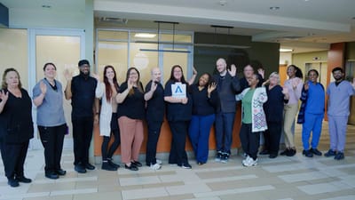 Staff members posing and waving in the facility lobby