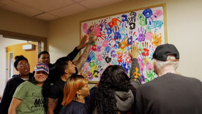 Residents and staff creating a colorful handprint mural