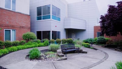 A landscaped outdoor space with seating near the facility entrance