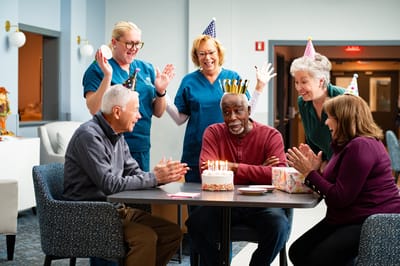 Celebration with residents and staff around a birthday cake