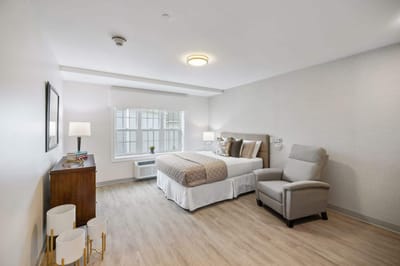 Bright, well-furnished resident room with a bed and chair