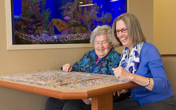 Residents enjoying a puzzle activity with staff assistance