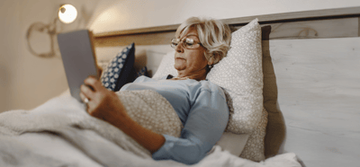Resident reading in bed with a cozy blanket