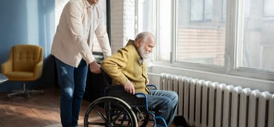 Staff assisting a resident in a wheelchair indoors