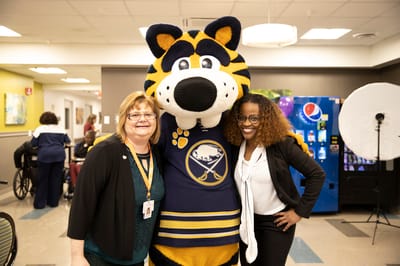 Staff and mascot posing together in a common area