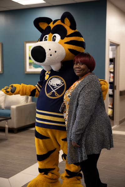 Staff member posing with a mascot in the lobby
