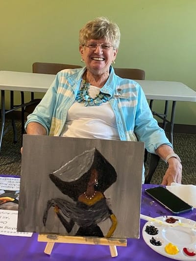 A senior woman painting at an activity table