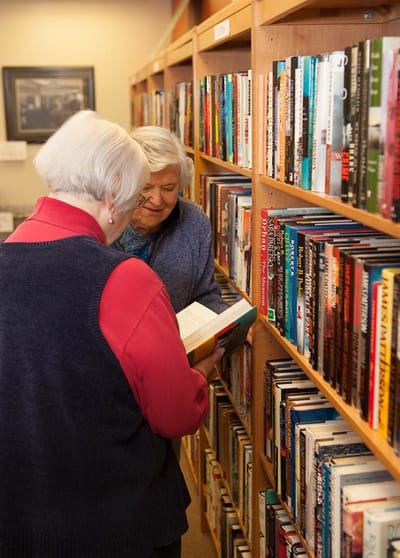 Two residents browsing books in a library area