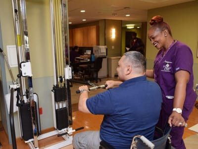 Staff assisting a resident with rehabilitation equipment
