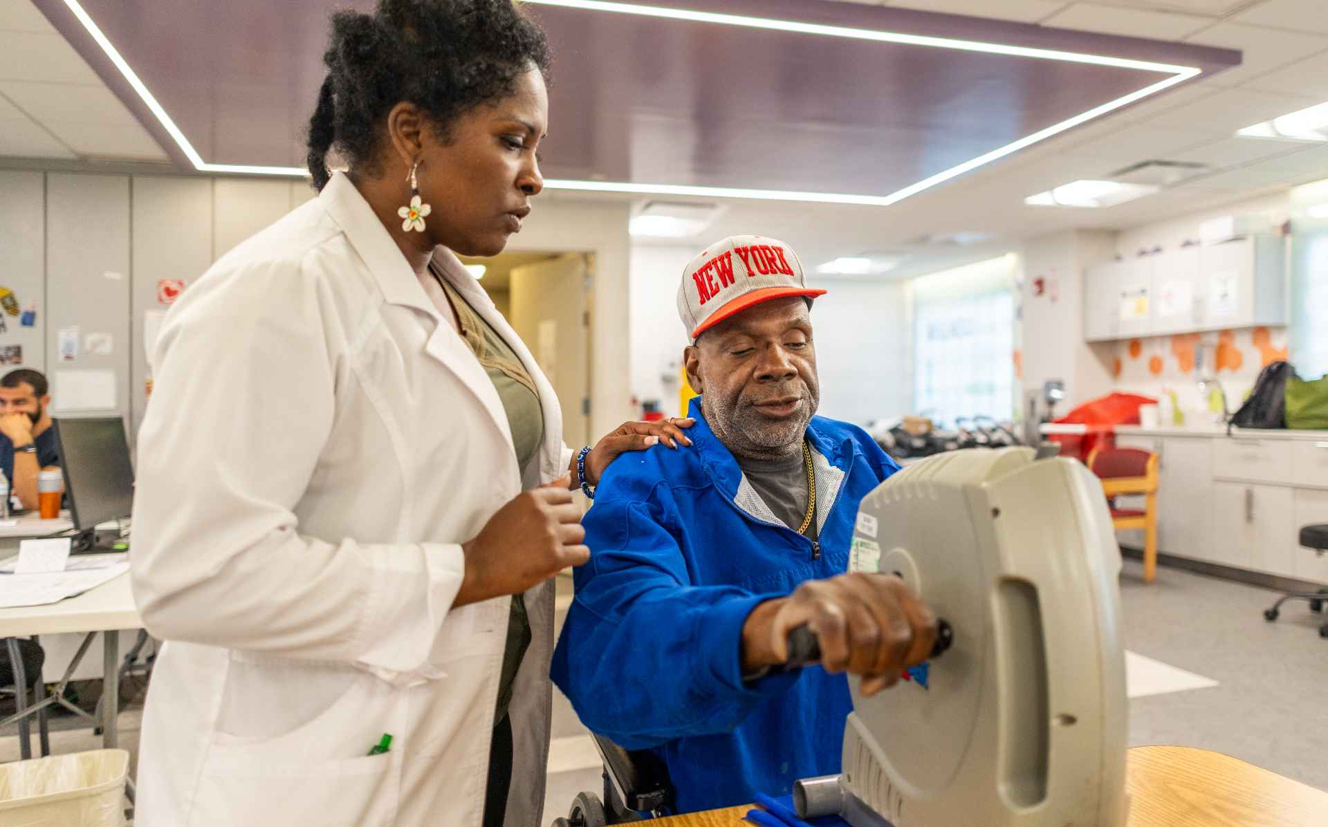 Resident using a therapy machine with staff assistance