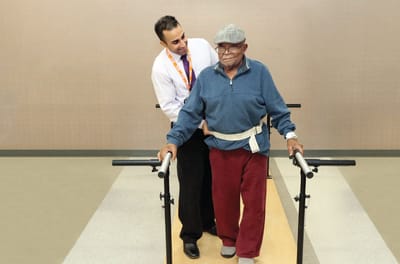 Staff assisting resident with walking aid in a therapy session