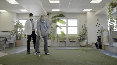 A resident practicing putting with staff assistance