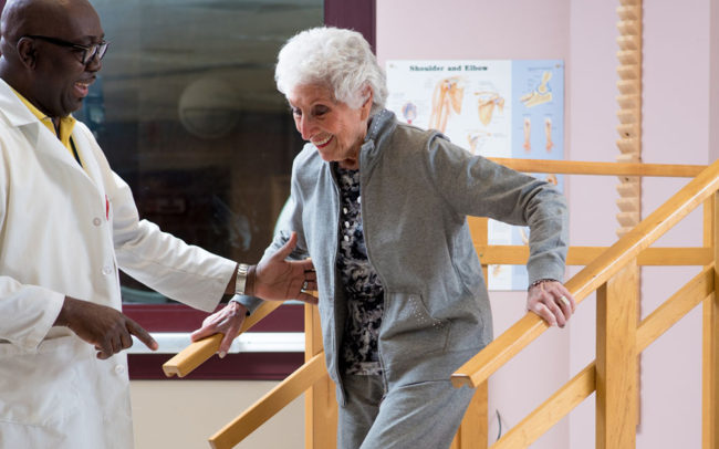 Therapist assisting a senior woman on steps