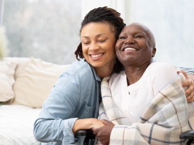 A caregiver and resident smiling together in a cozy indoor setting