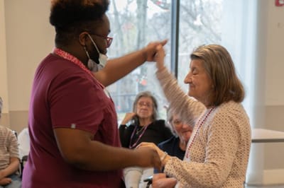 Staff dancing with a resident in a bright activity room