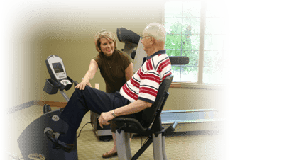 A staff member assisting a resident with exercise equipment