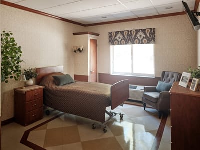 A well-furnished resident room with a bed and chair