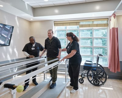 Staff assisting a resident with therapy exercises