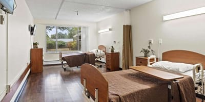 A shared resident room with two beds and a view outside