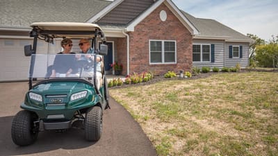Residents enjoying a golf cart ride outside a facility