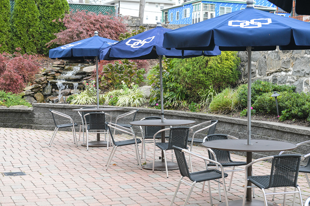Patio area with umbrellas and seating near a waterfall