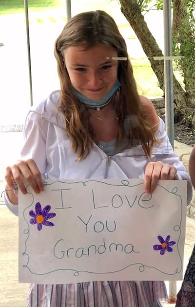 A girl holding a sign for her grandmother