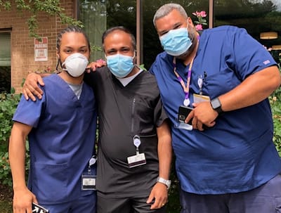 Three staff members smiling outside the facility