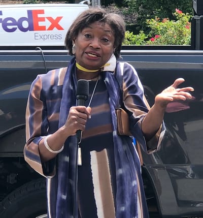 A woman speaking with a microphone outdoors