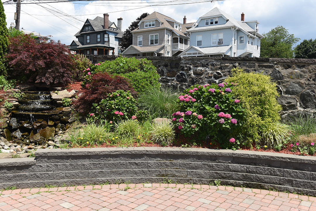 A landscaped garden with a waterfall and blooming flowers