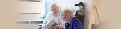 Two seniors reading a newspaper in a cozy room