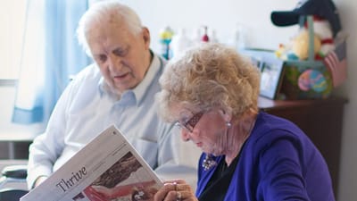 Holiday Retirement Village, nursing home in Evansville, IN — Seniors reading a newspaper together in a cozy setting