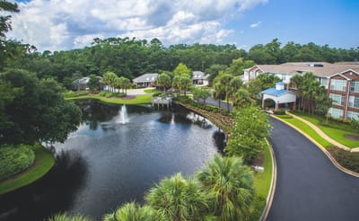 Aerial view of a scenic senior living campus with water feature