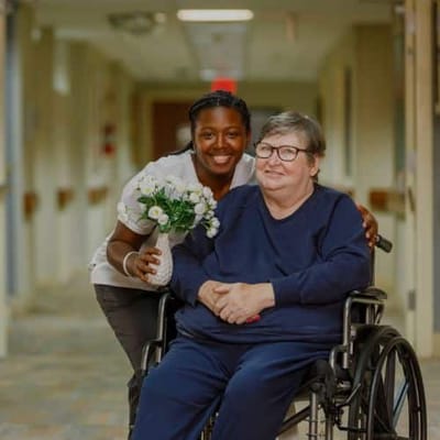 Staff member helping a resident in a hallway