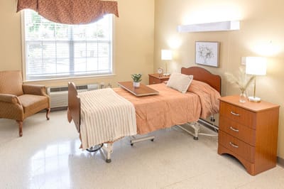 Cozy resident room with a bed, chair, and warm decor