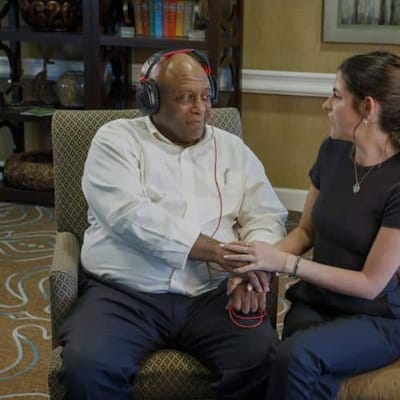A resident enjoying music with staff support