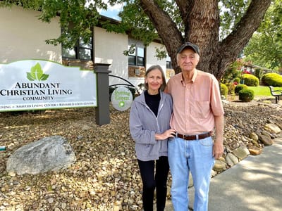Couple standing outside the Abundant Christian Living Community sign