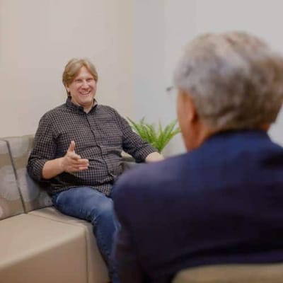 Two men engaged in a conversation on a sofa