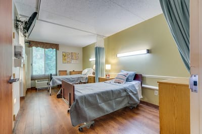 A shared resident room with two beds and light decor