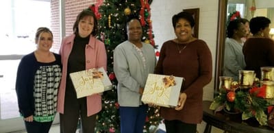 Staff celebrating with gifts near a Christmas tree
