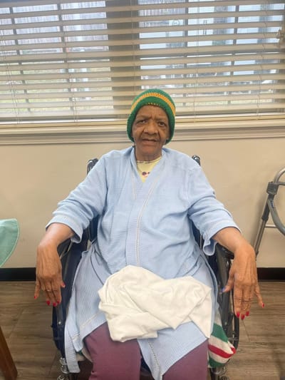 Elderly woman smiling in a wheelchair indoors