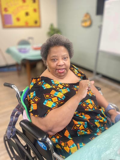Resident in a colorful dress smiling and gesturing