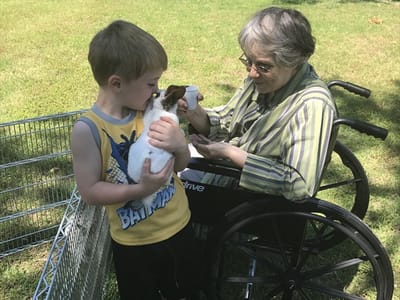 Resident interacting with a child and a rabbit outdoors