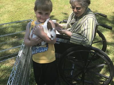 A boy holding a rabbit next to a woman in a wheelchair