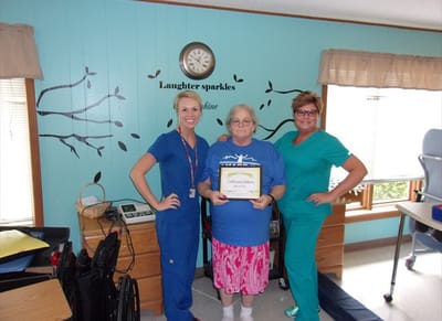 Staff and resident celebrating with a certificate.