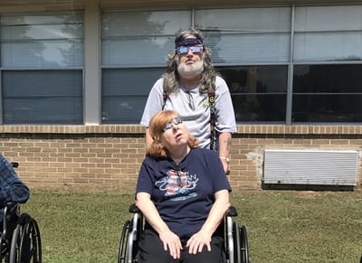 Two residents in wheelchairs outside a facility