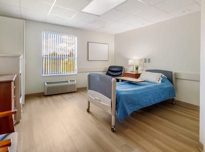 Bright private resident room with a bed and chair