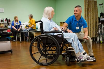 Staff assisting a resident in a therapy room