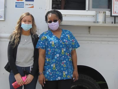 Two staff members in front of a food truck