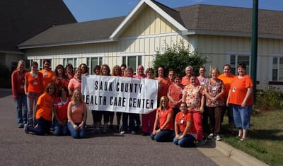 Staff in matching shirts posing with a large banner