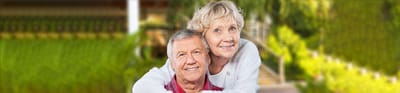Meadowbrook Senior Living at Black River Falls, nursing home in Black River Falls, WI — Happy senior couple smiling outdoors in a garden setting